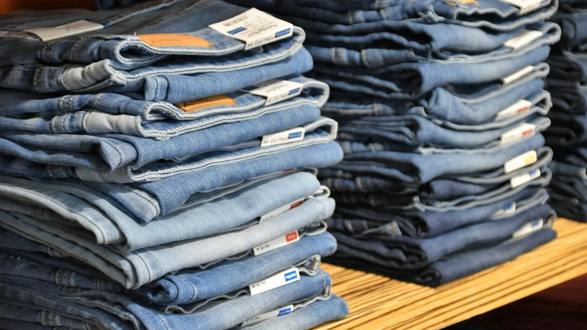 Pile di jeans blu piegati e impilati: il tessuto che il mondo chiama jeans nasce dal blu di Genova