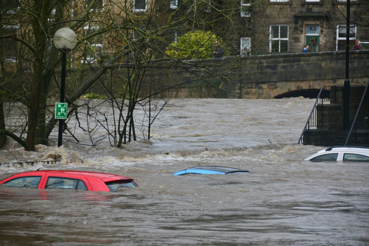 Strada allagata con auto sommerse dall'acqua durante un'alluvione in un centro abitato