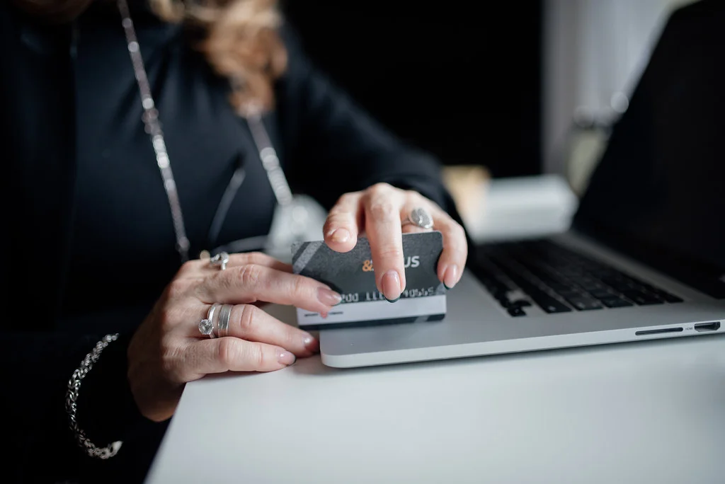 Persona con la carta di credito in mano davanti a un computer portatile mentre acquista una polizza online